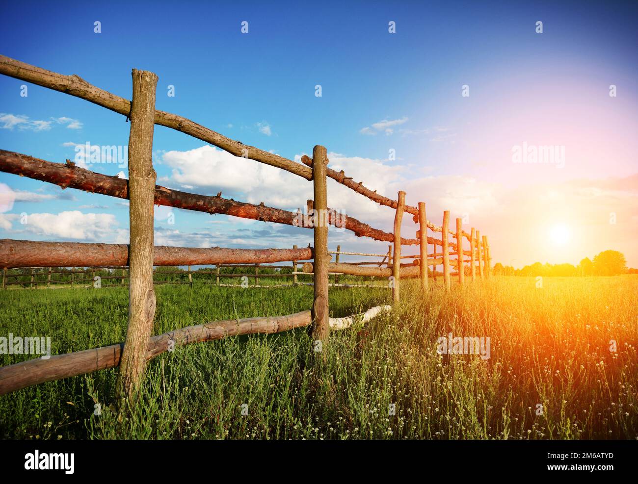 Fence in the green field under blue cloud sky Stock Photo - Alamy
