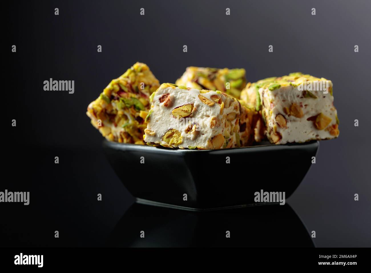 Traditional Turkish delight in a small black dish on a black reflective background. Stock Photo