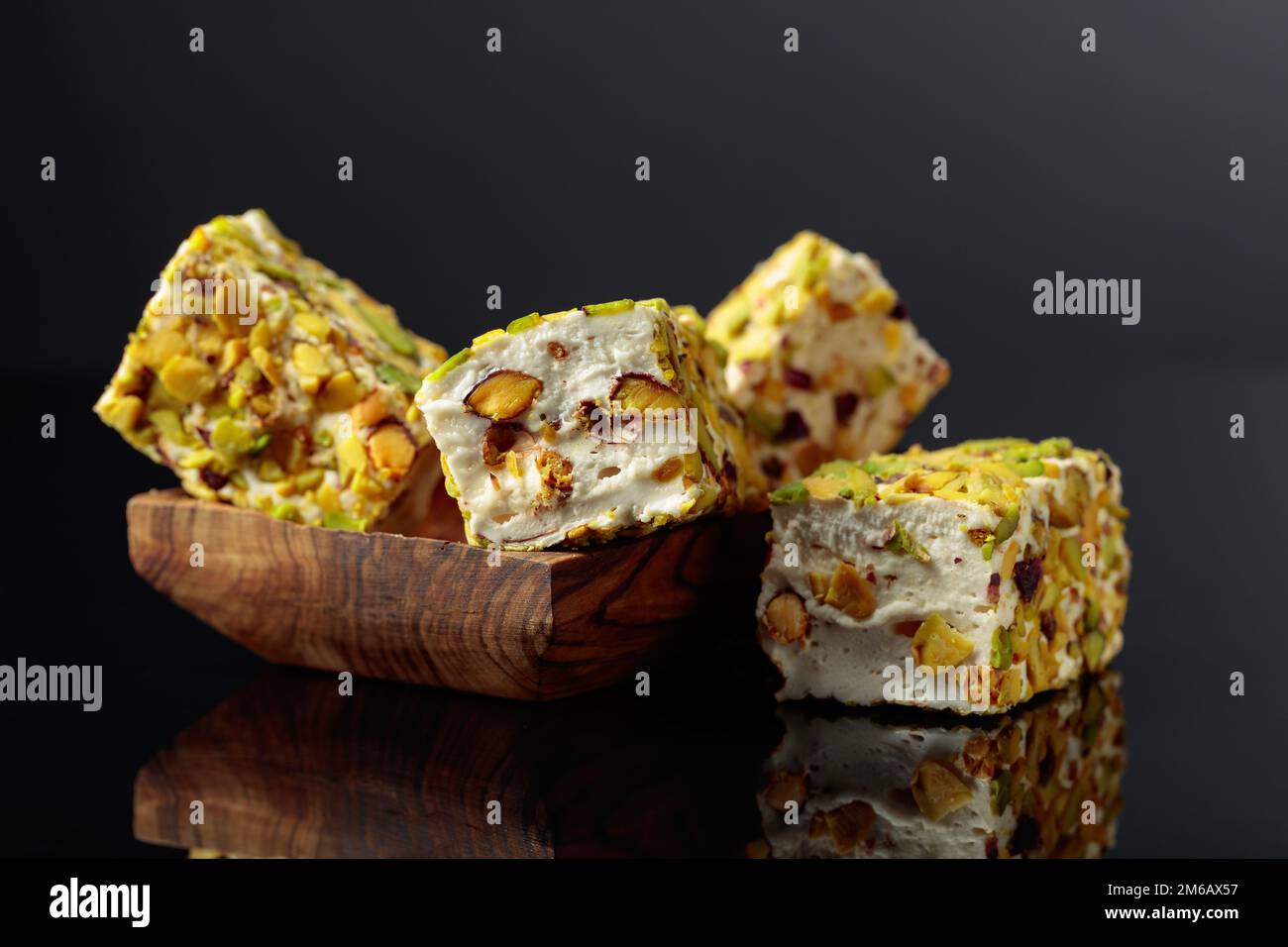Traditional Turkish delight in a wooden dish on a black reflective background. Stock Photo