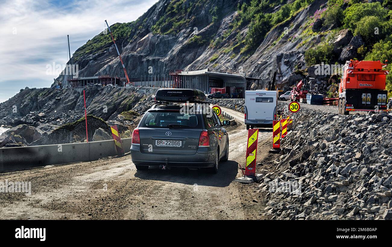 Road construction site, car driving over dusty track on rocky coast, coastal road, Lofoten, Norway Stock Photo