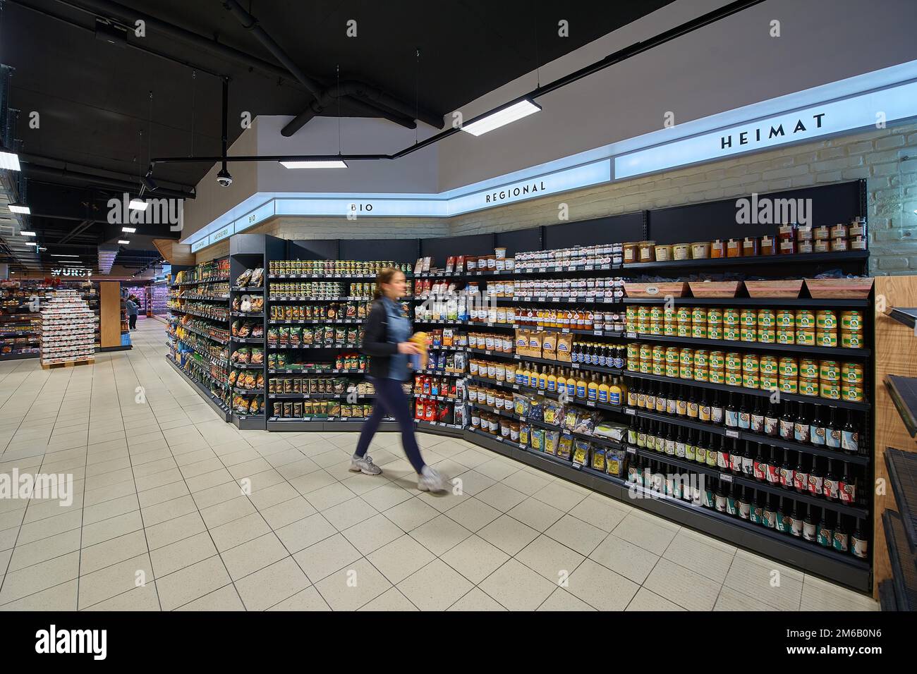 Saleswoman (blurred) in front of a shelf with regional products, Edeka