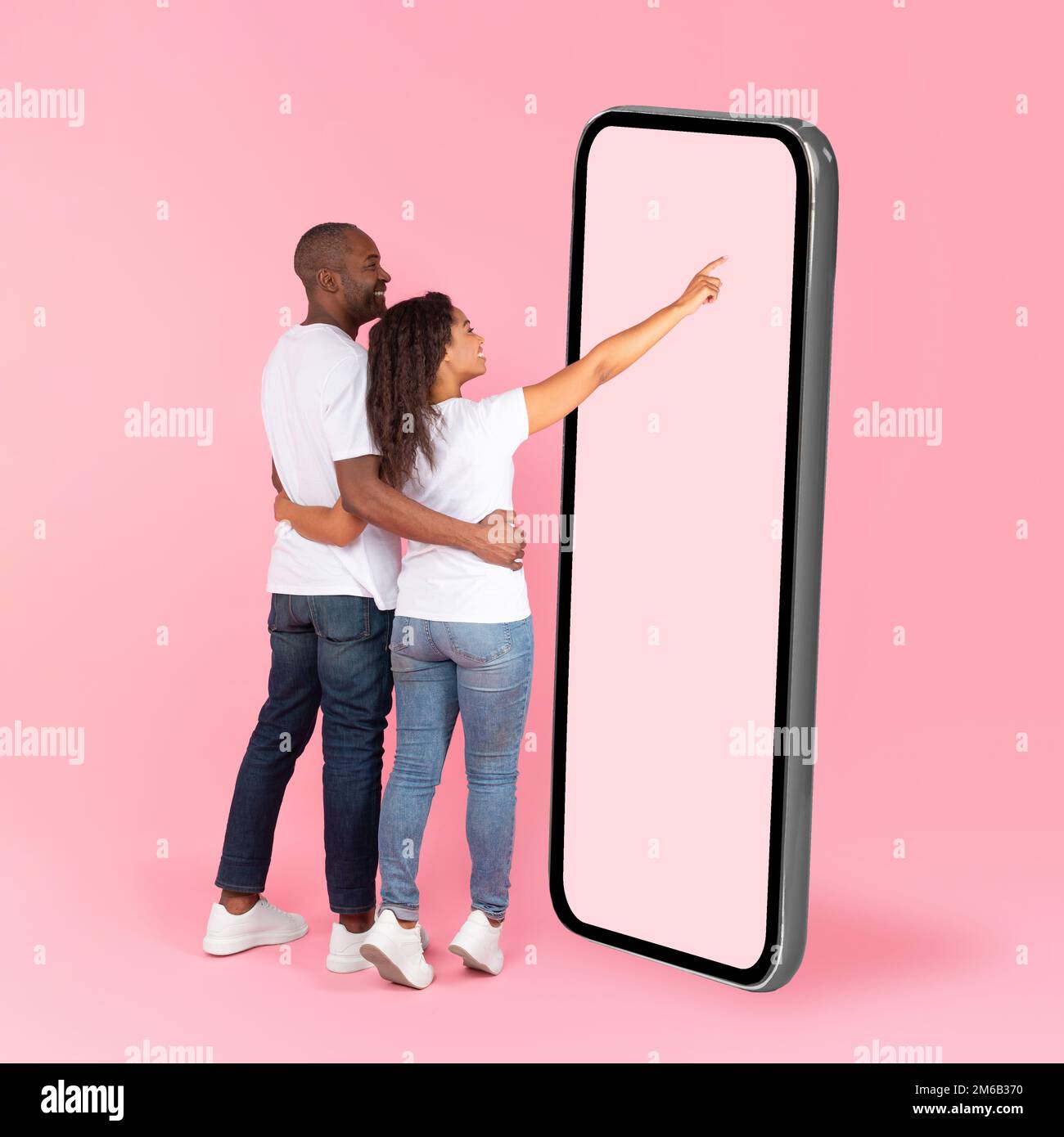 Rear back view of black spouses using big smartphone with blank screen, woman touching huge display panel, mock up Stock Photo