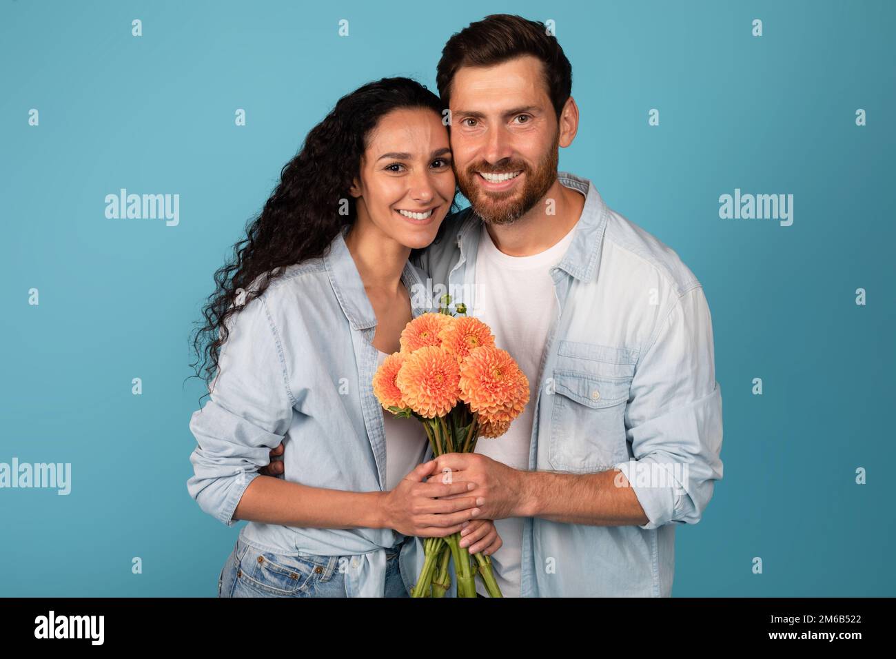 Happy young international couple hold bouquet of flowers, celebrate holiday, enjoy date and romantic Stock Photo
