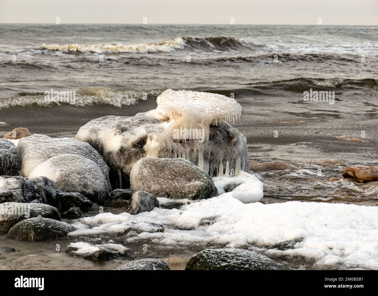 various ice formations on rocks and sandbars on the seashore, ice ...