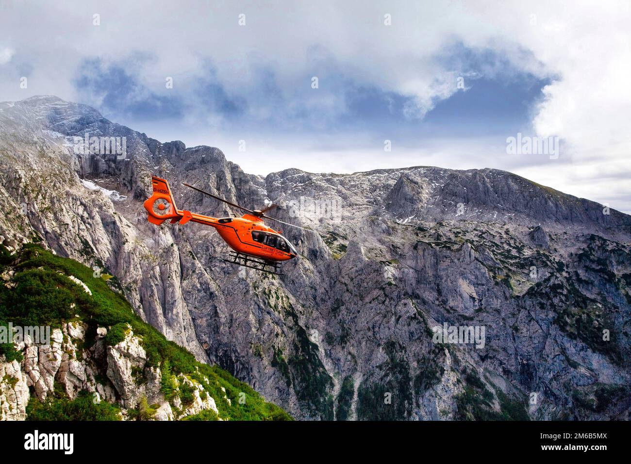 A medical helicopter removes a patient from high altitude in the Alps of Germany. Stock Photo