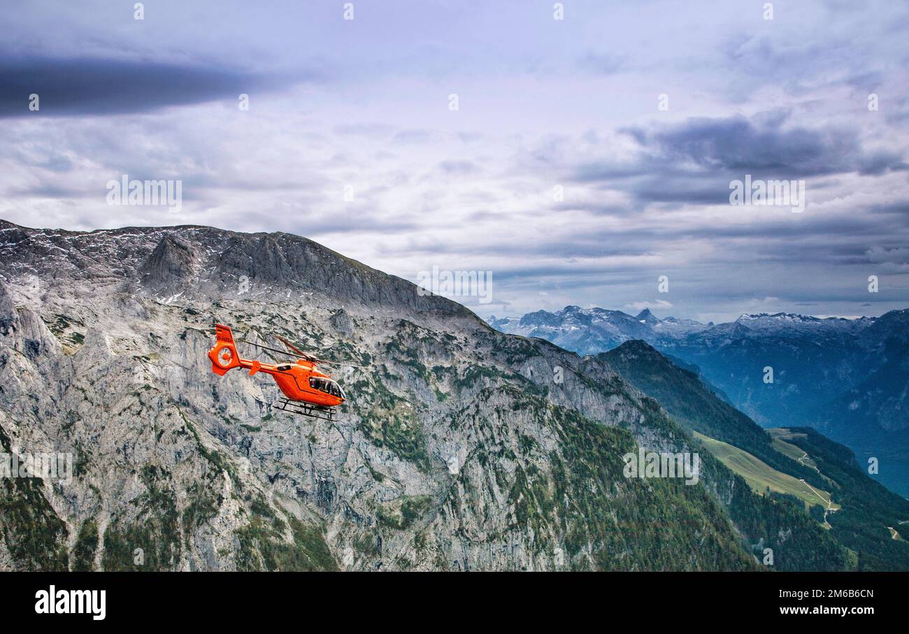 A medical helicopter transports injuries parties from high altitude in the German Alps. Stock Photo