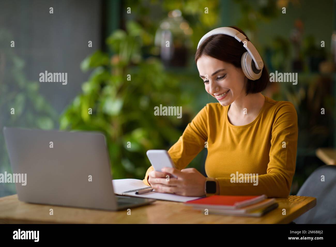 Cheerful young IT woman using headphones while working online Stock Photo