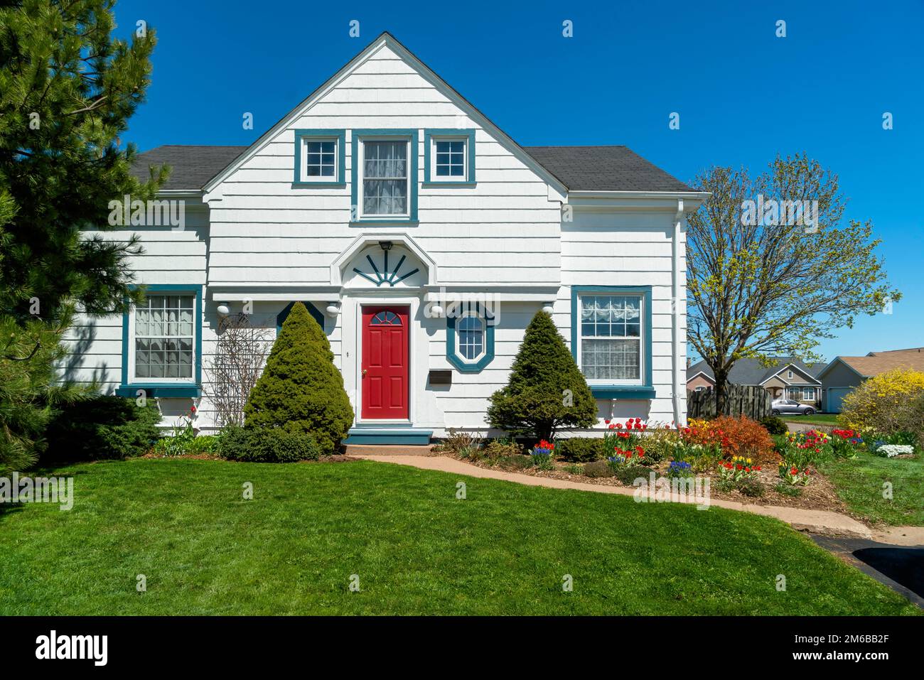 An older style tradional home with flower beds full of springtime flowers. Stock Photo