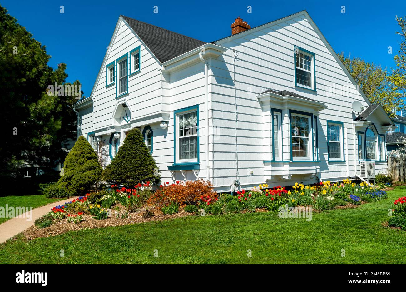 An older style tradional home with flower beds full of springtime flowers. Stock Photo