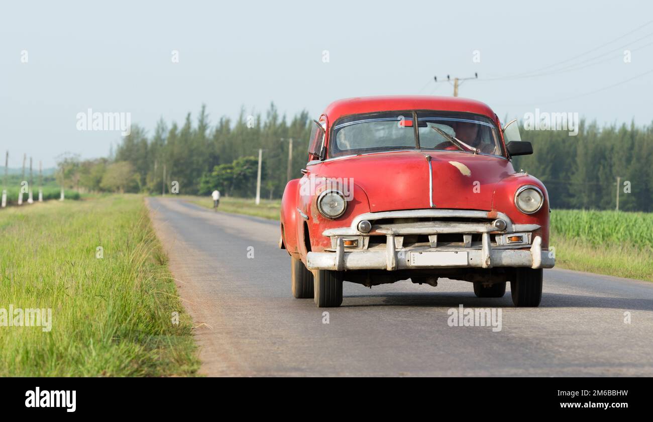 Blue American classic car traveling on the road in the countryside of Cuba Stock Photo