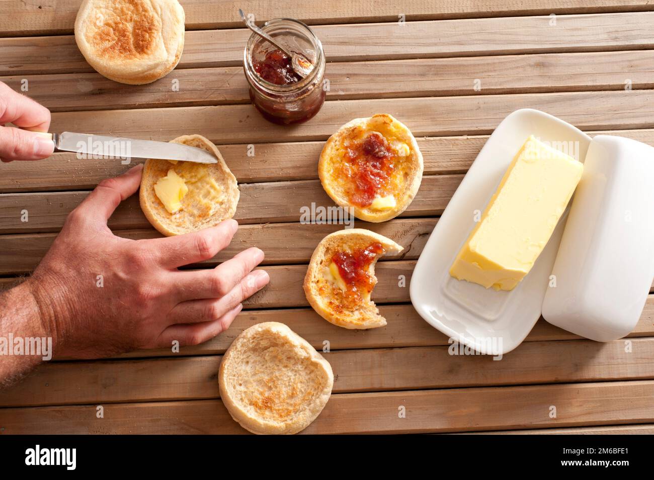 Man buttering a crumpet for breakfast Stock Photo