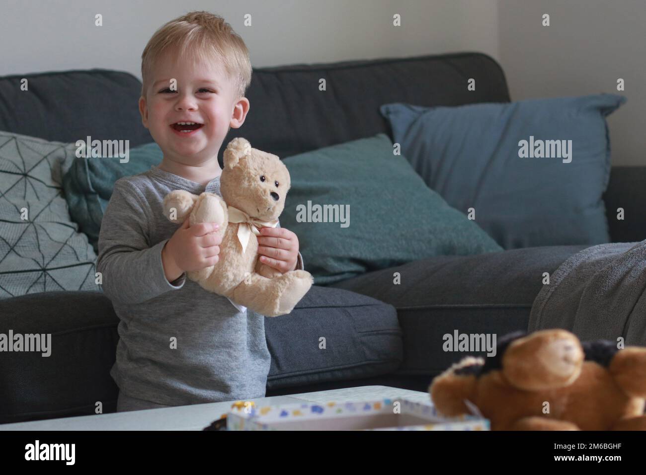 portrait of cute happy little boy playing with teddy bear in living ...