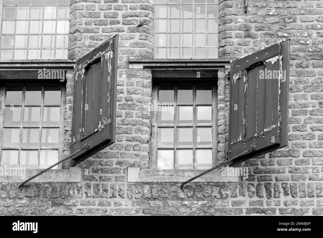 A grayscale of old windows on a brick building Stock Photo - Alamy