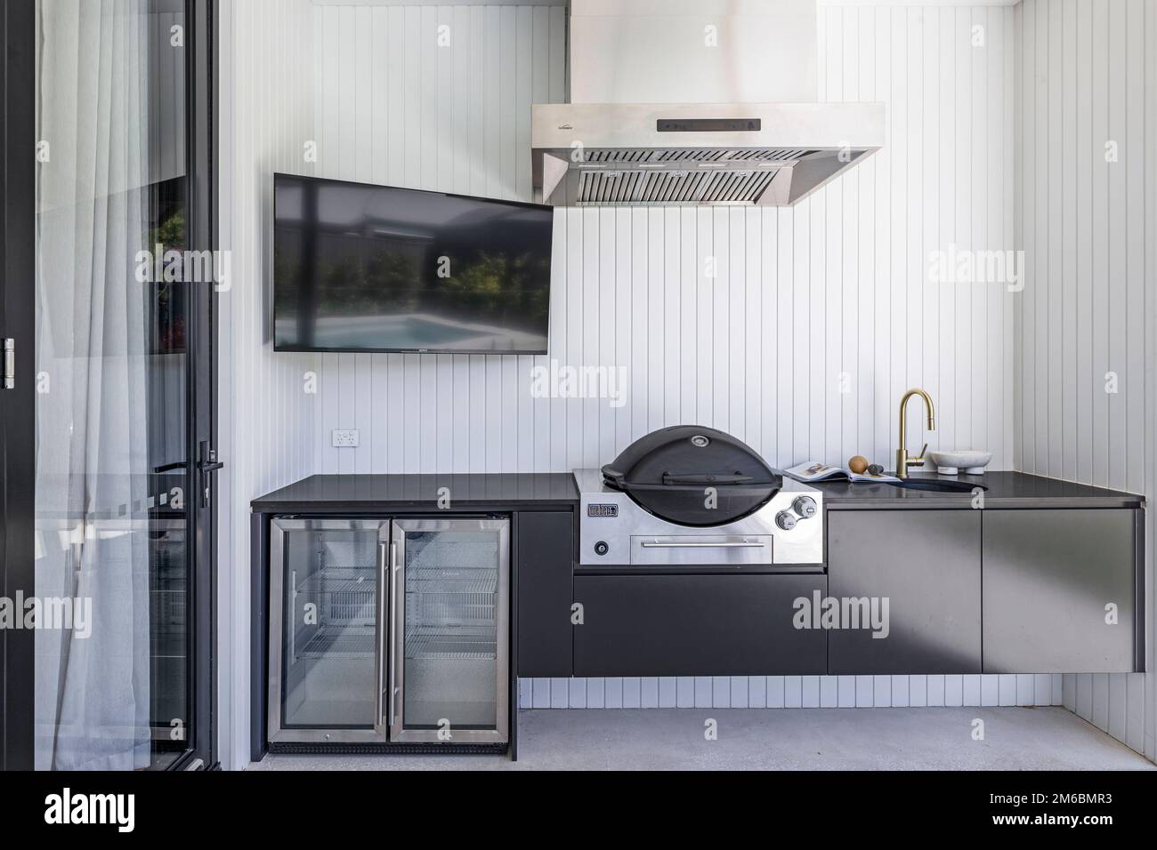 Outdoor white kitchen with barbecue, drink fridge and sink Stock Photo