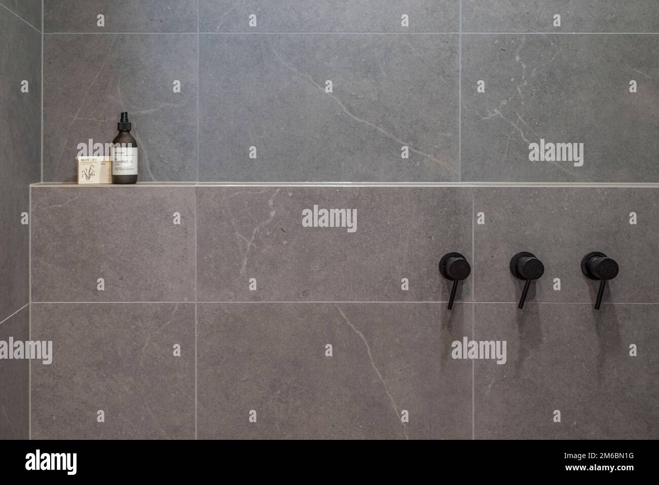 tiled bathroom shower area showing black hot and cold taps Stock Photo ...
