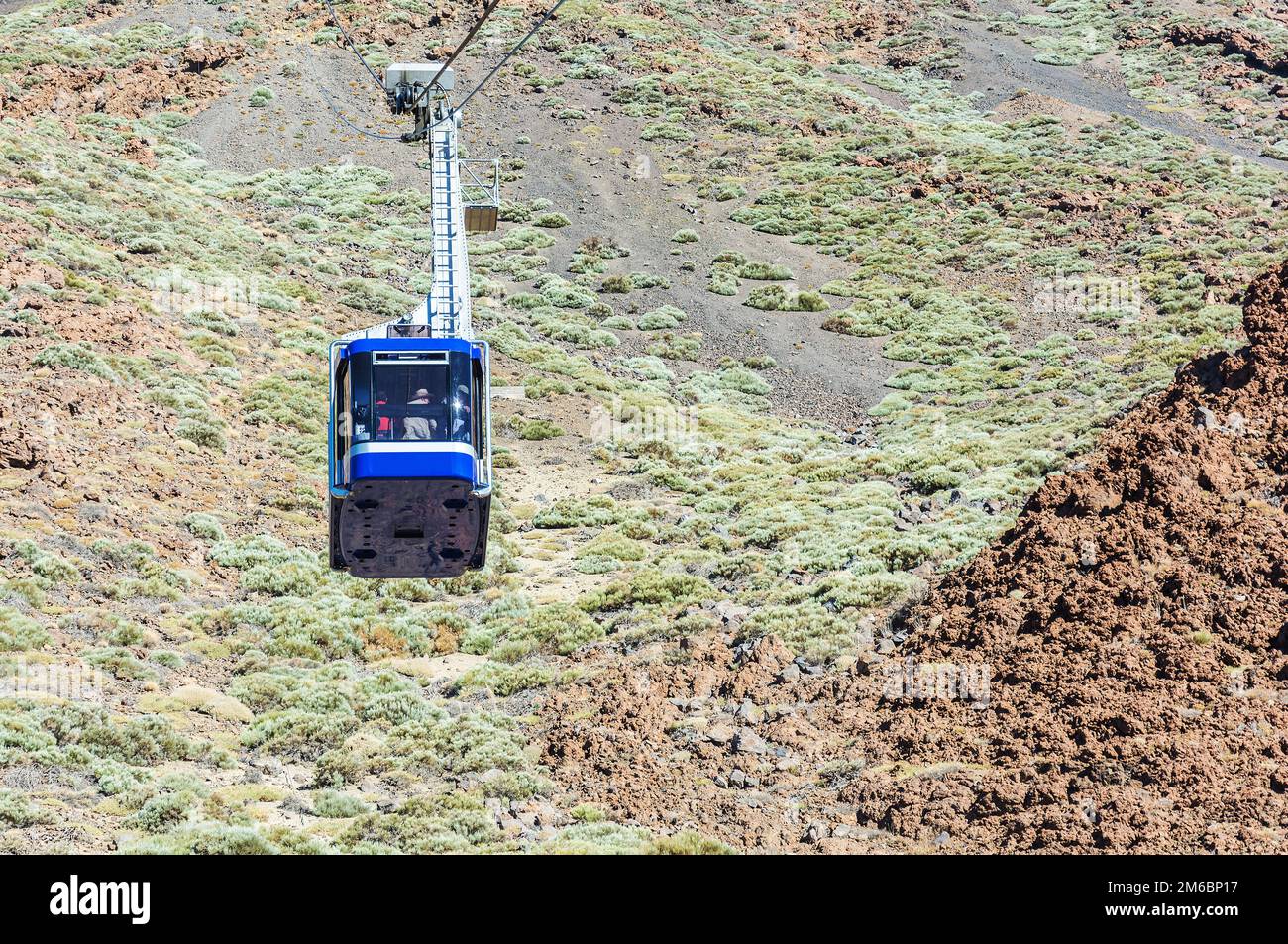 Blue cabin cable car with tourists climbing ropes stretched to the volcano Teide on Tenerife island. Stock Photo