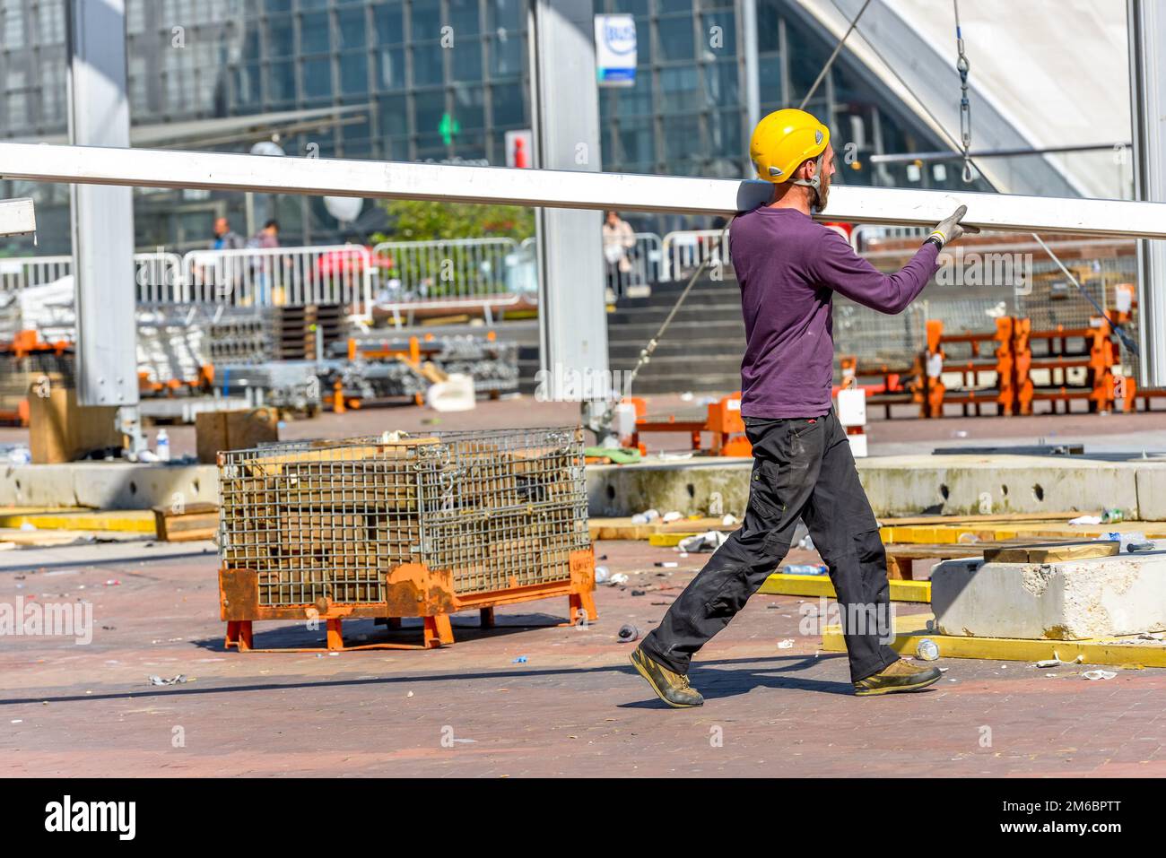 La defense, France- April 10, 2014: Construction worker carrying a steel beam on his shoulders Stock Photo