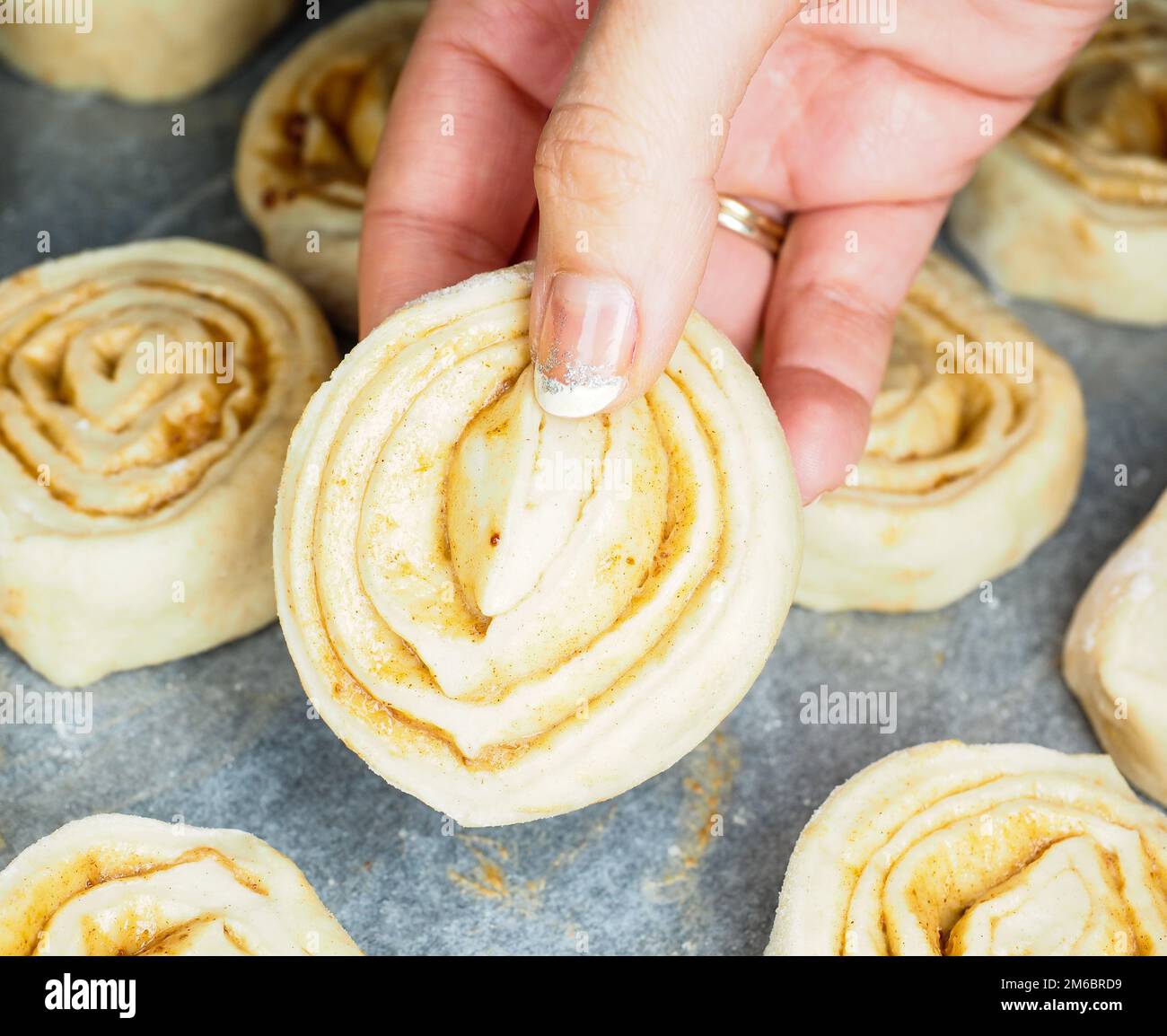Closeup of raw cinnamon roll and cinnamon buns on baking paper Stock Photo