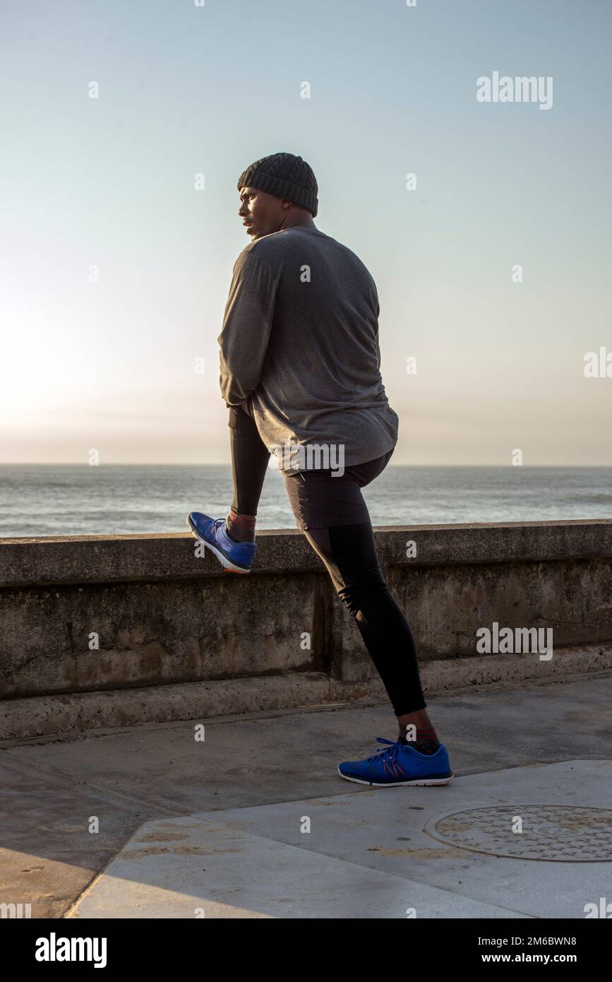 Man with beanie on head does stretch exercises Stock Photo