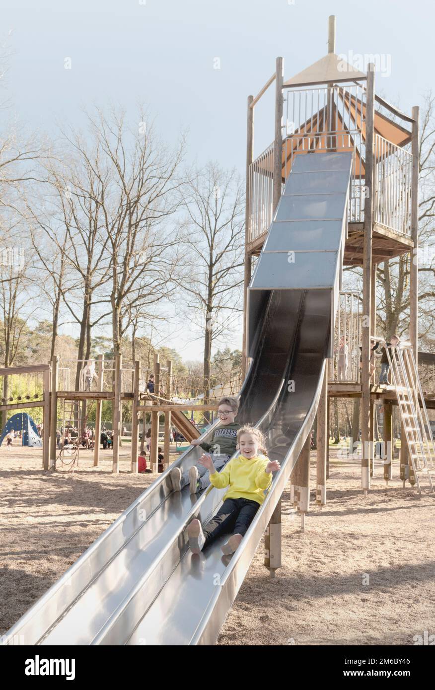 Children slide down a high slide in the park Stock Photo