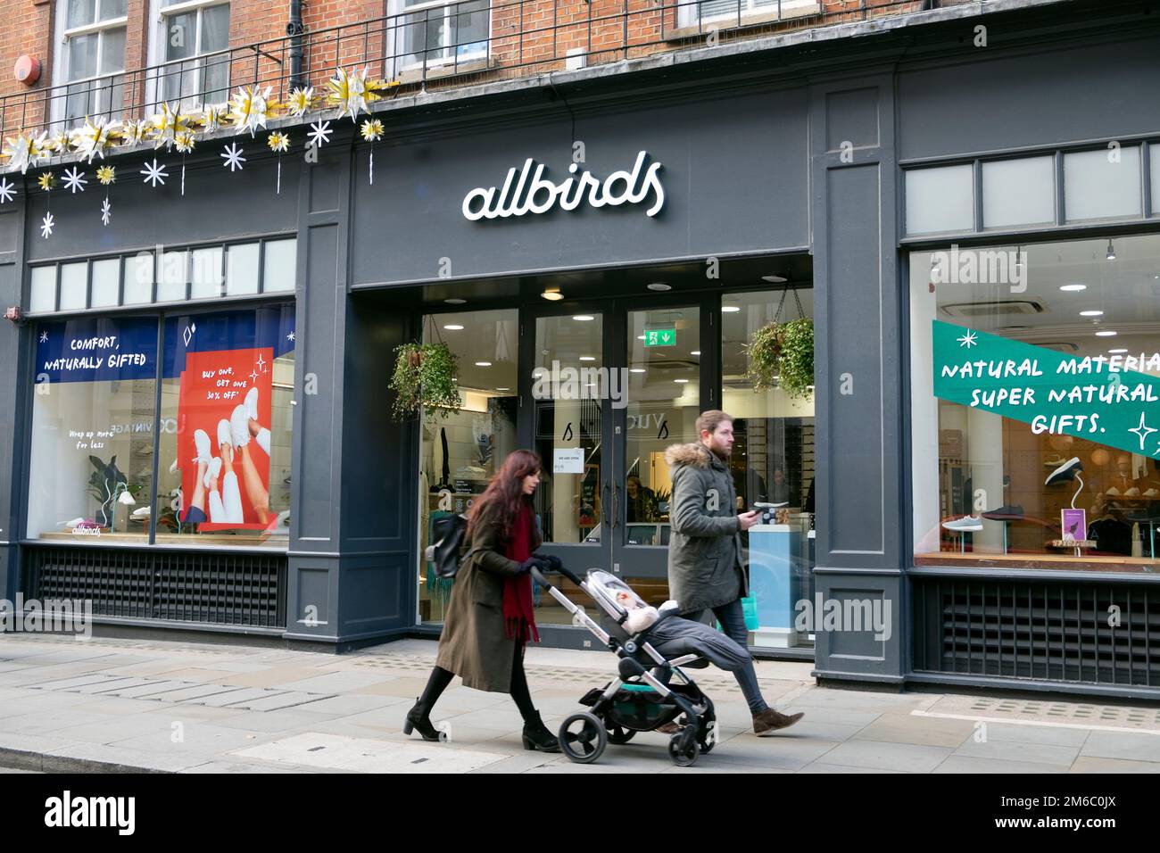 Allbirds American sustainable shoe store exterior and family people walking with baby in pushchair buggy Covent Garden London UK  KATHY DEWITT Stock Photo