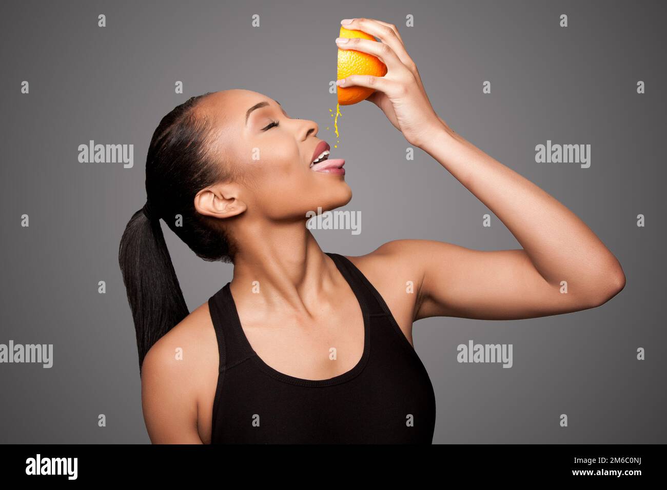 Happy healthy black asian woman squeezing orange juice fruit Stock Photo