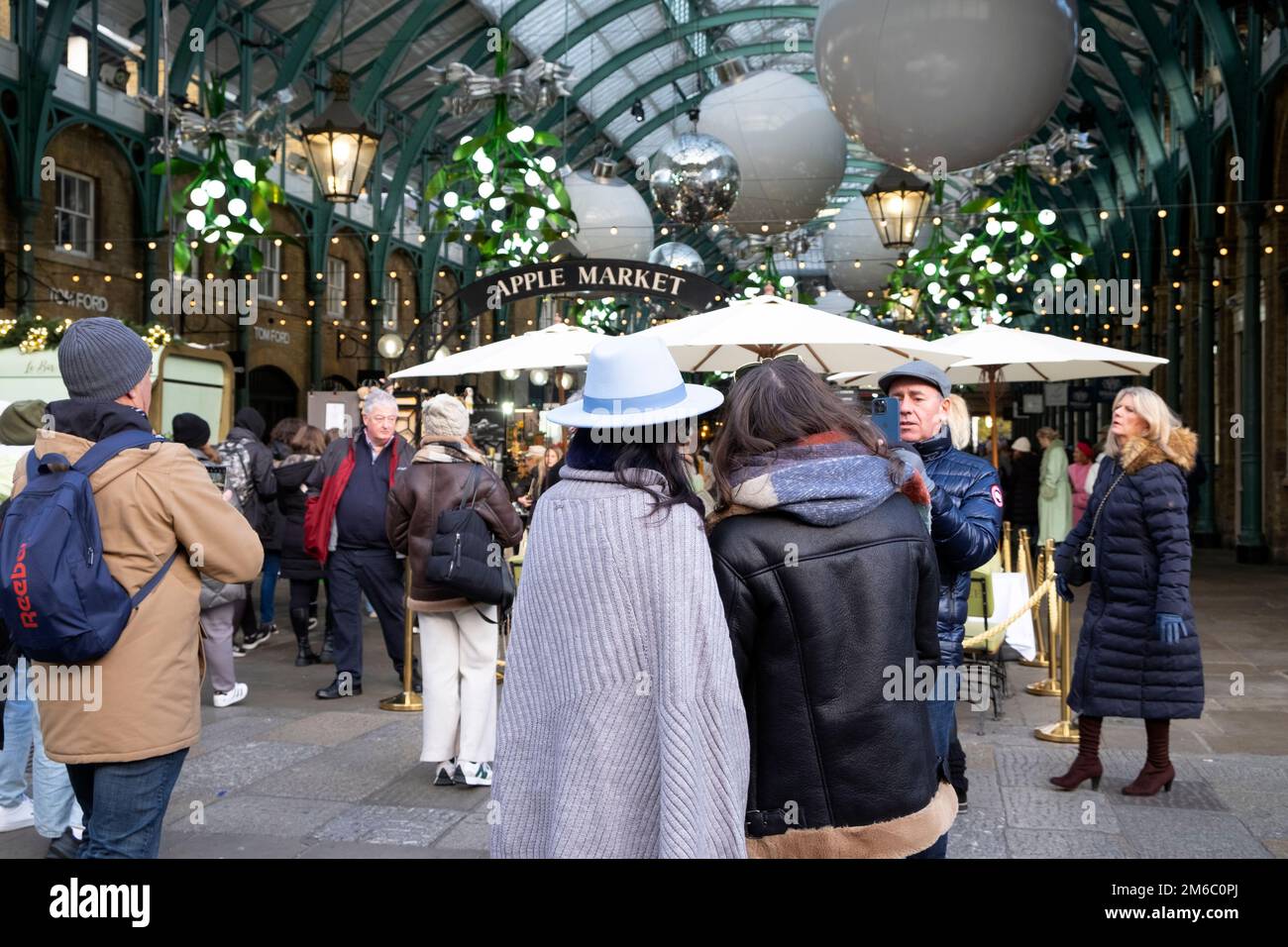 Rear back view of visitors crowd of tourists and decorations at Apple Market at Christmas December 2022 Covent Garden London England UK KATHY DEWITT Stock Photo