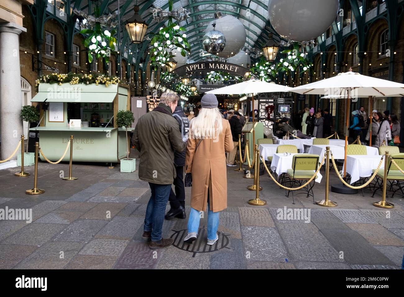 Rear back view of visitors tourists decorations at Apple Market at Christmas December 2022 Covent Garden London England UK KATHY DEWITT Stock Photo