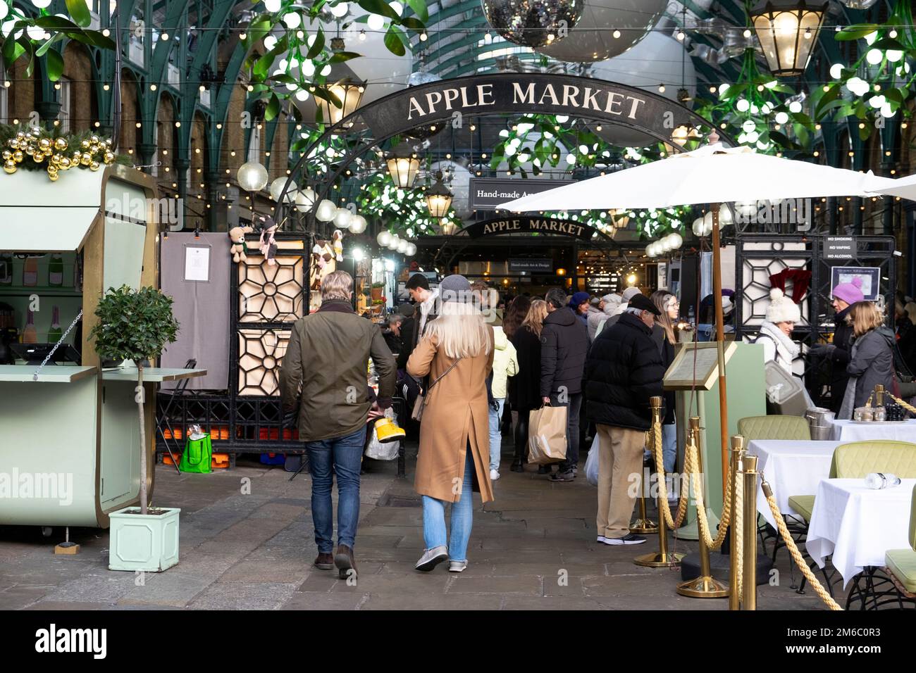 Rear back view of visitors tourists decorations at Apple Market at Christmas December 2022 Covent Garden London England UK KATHY DEWITT Stock Photo