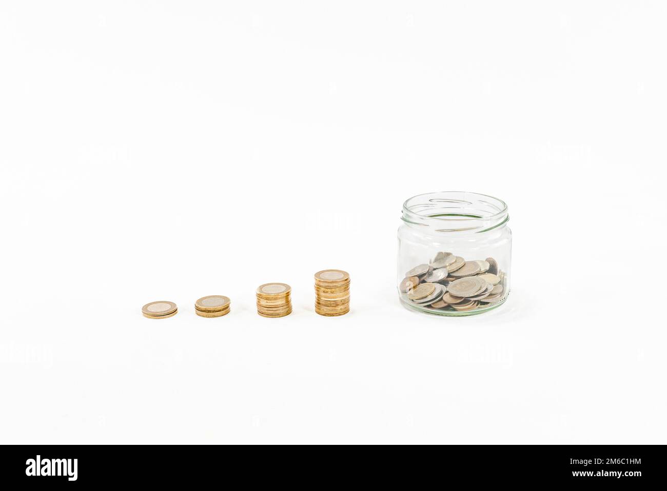 Clear glass jar with stacked coins money box, penny or piggy bank on white background. Saving money concept idea photo hd. Saving money box or piggy. Stock Photo
