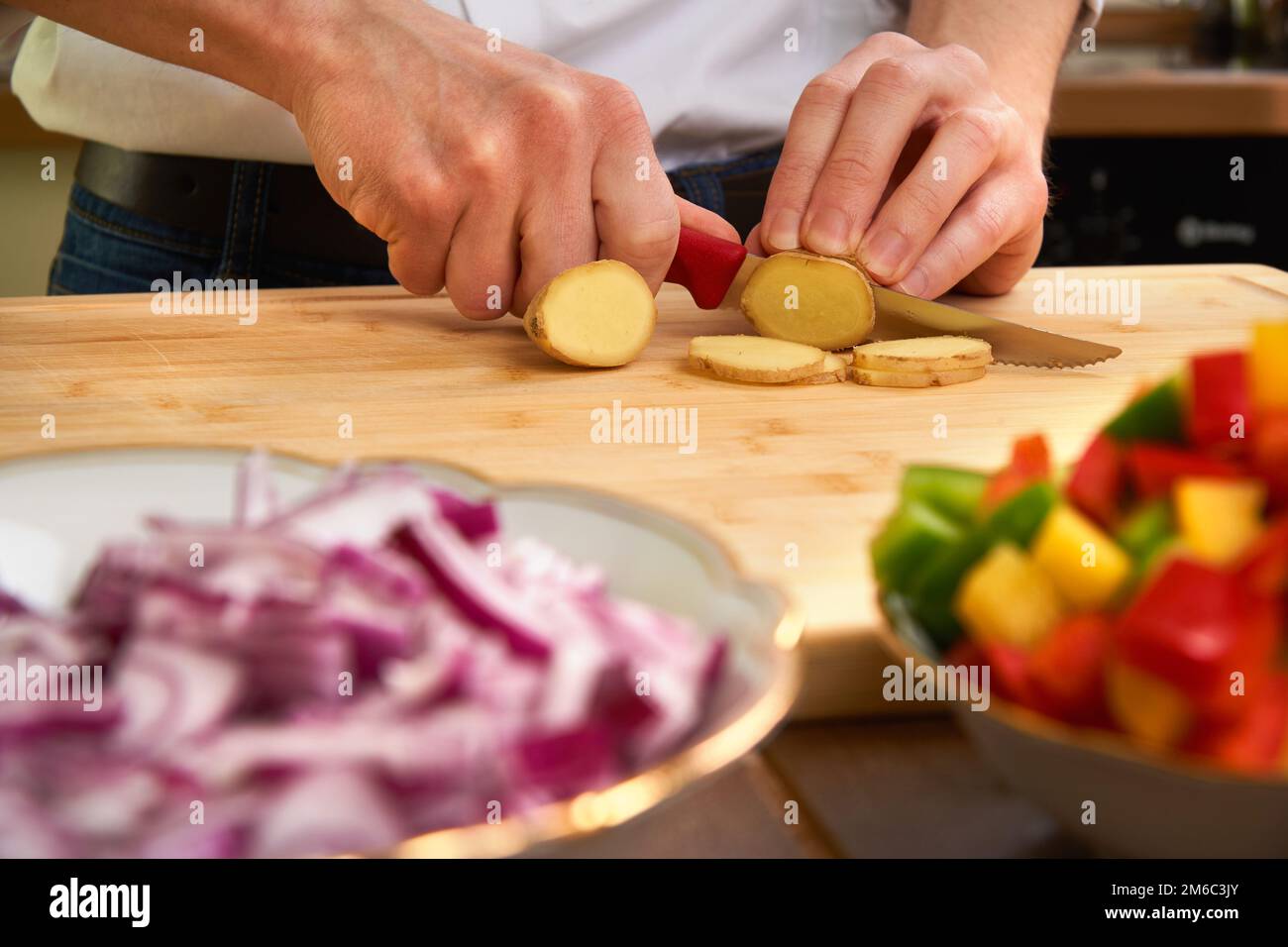 Man's hands cutting fresh tomatos in the kitchen, preparing a meal for lunch. Topdown view. Stock Photo