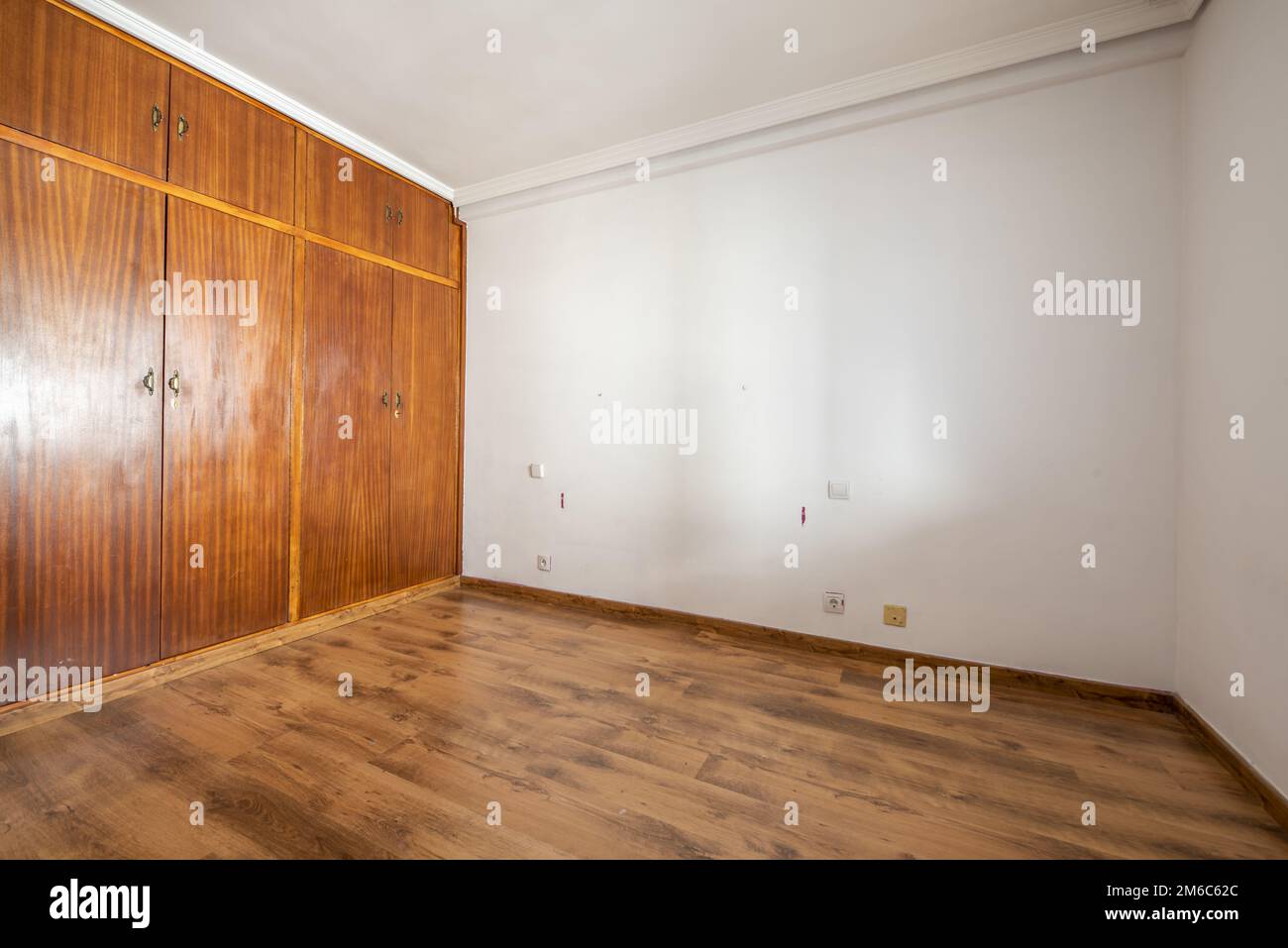 Empty room with built-in wardrobe with old sapele wood doors and dark wooden floors Stock Photo