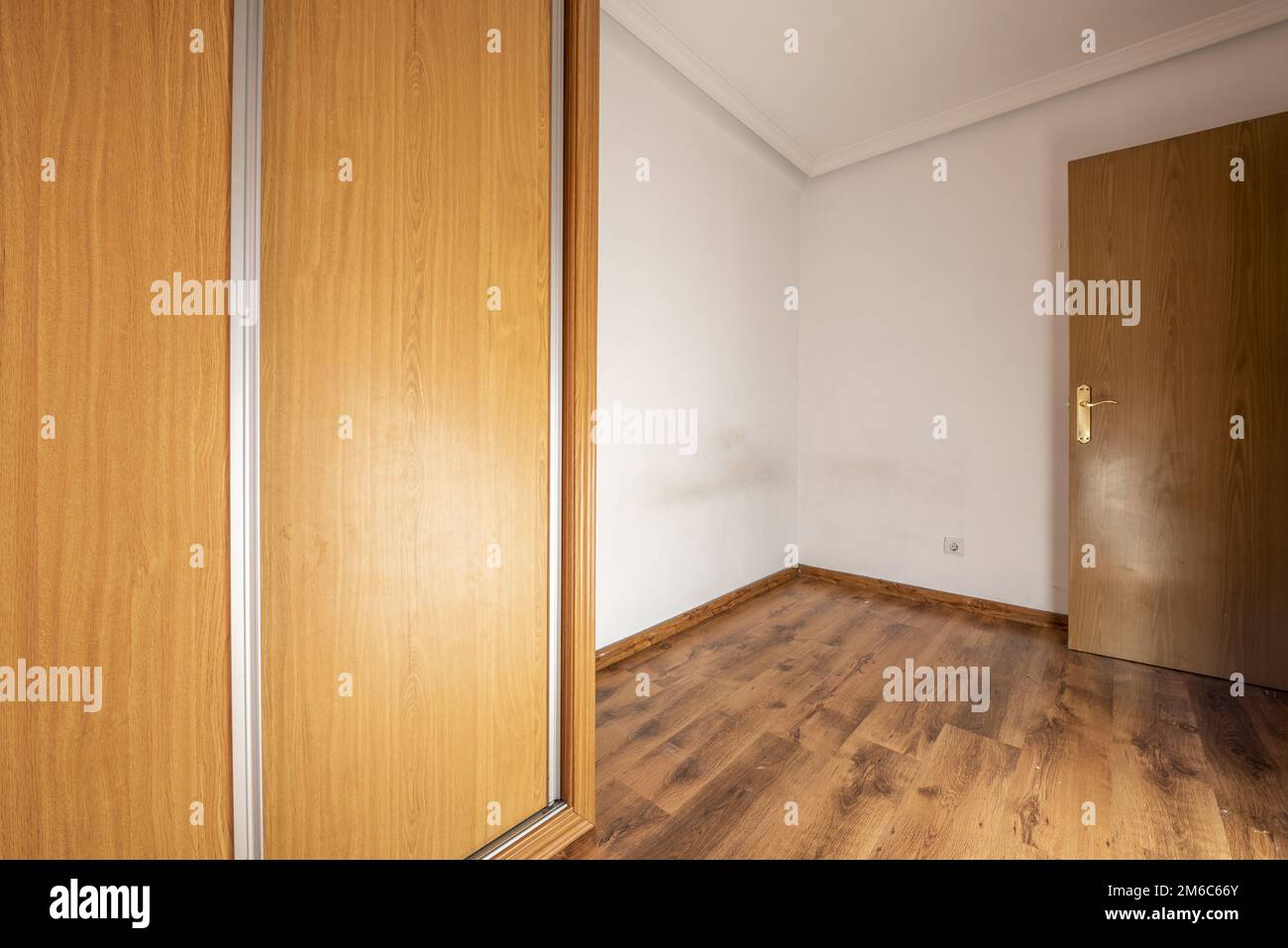 Empty room with built-in wardrobe with aluminum-edged oak sliding doors and dark wooden flooring Stock Photo