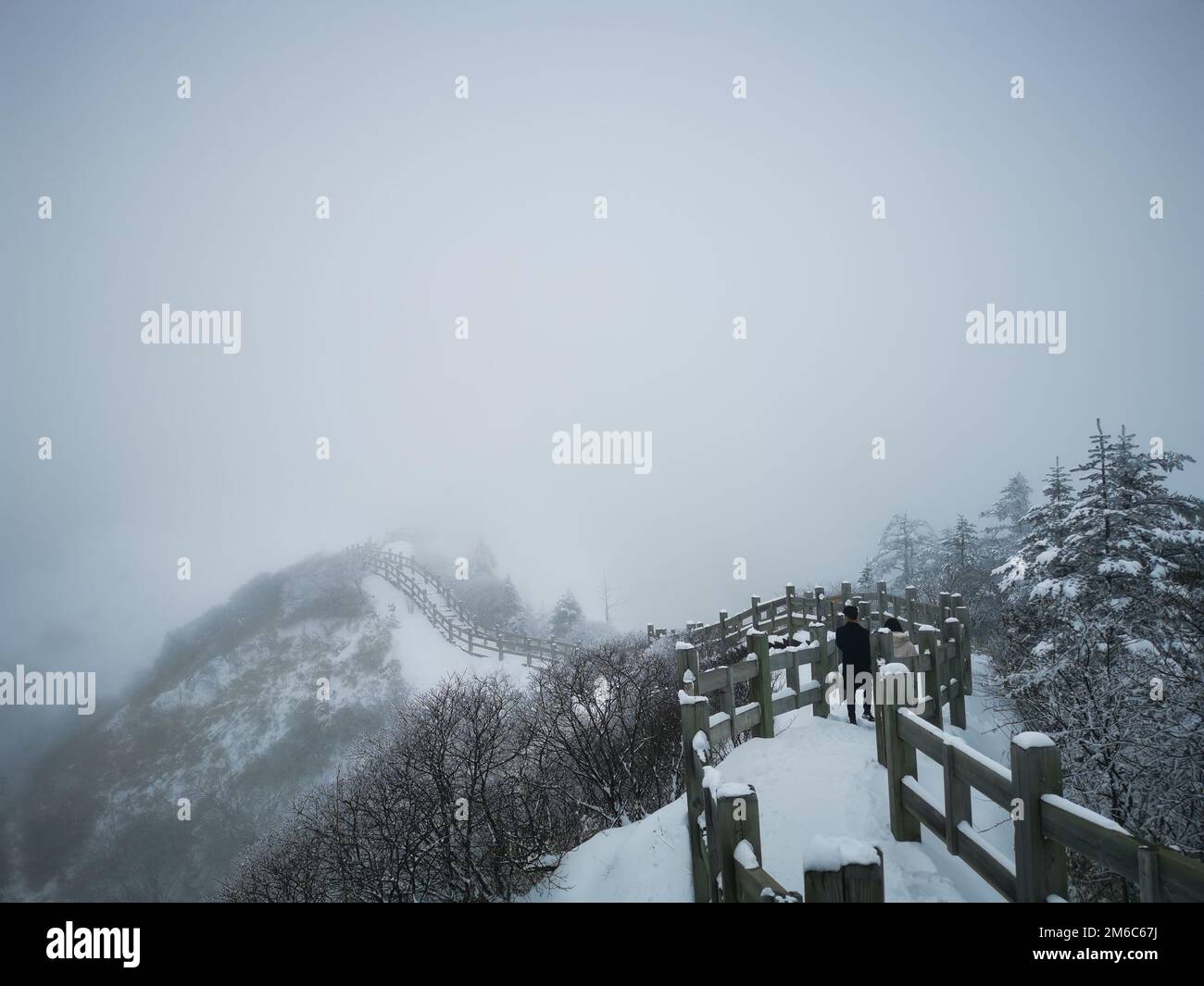 A beautiful view of a man walking on a pathway covered with snow on a ...