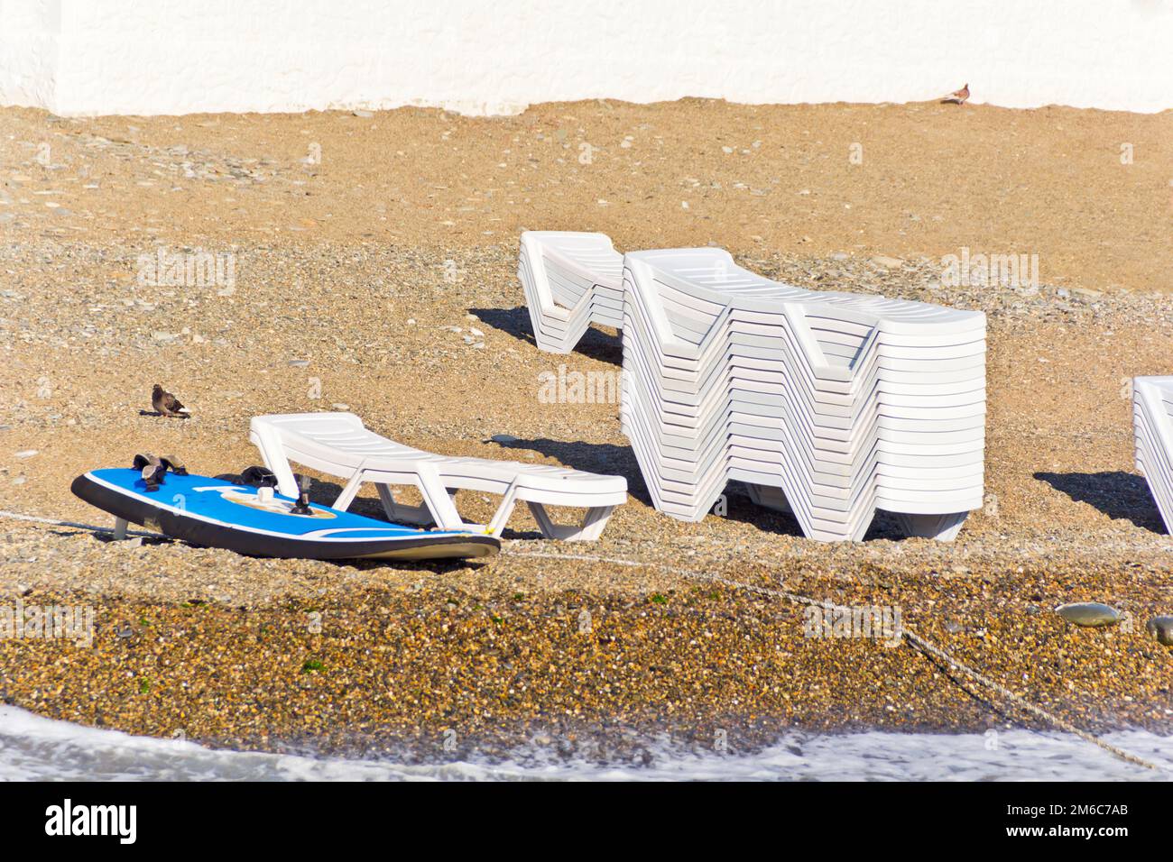 Empty beach with sun loungers and surfboard Stock Photo