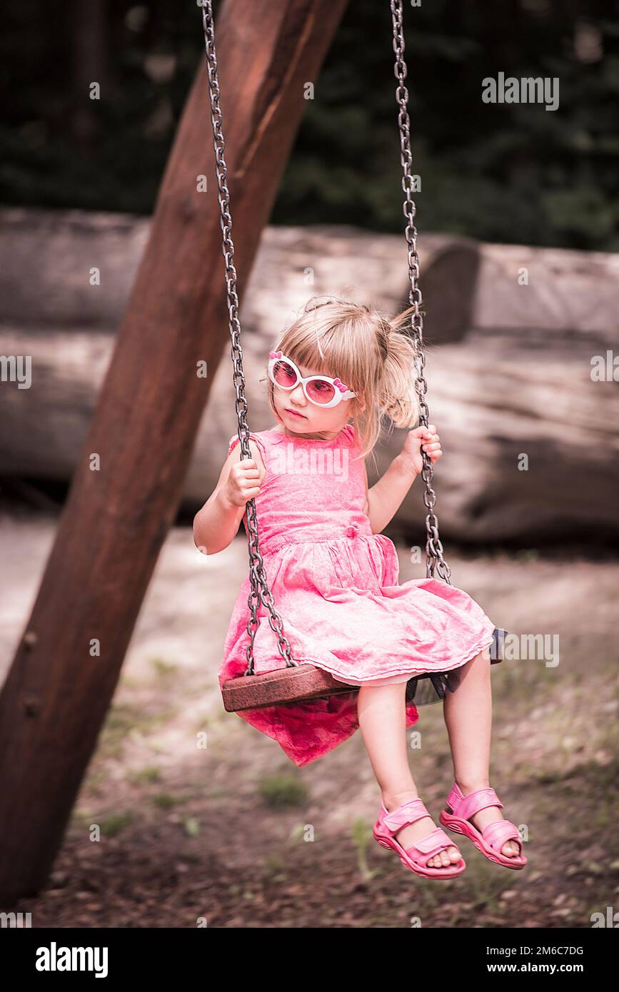Little blond girl on a swing Stock Photo