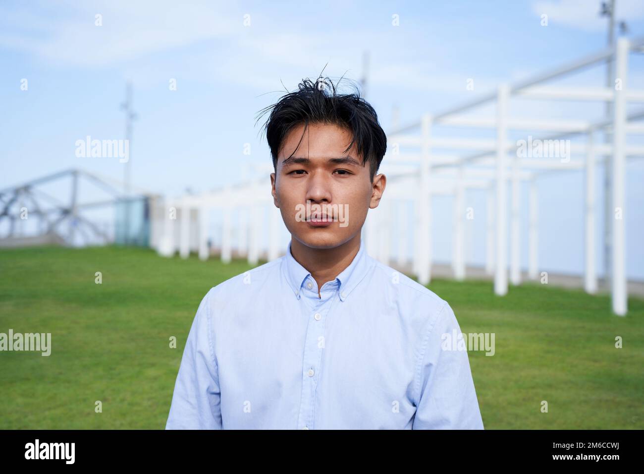 Looking at the camera portrait of an serious Asian guy young standing outdoors Stock Photo
