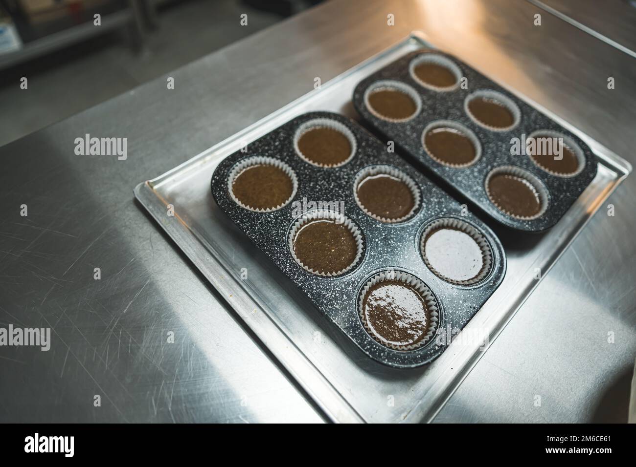 Cupcake liners filled with chocolate dough in two cupcake pans placed
