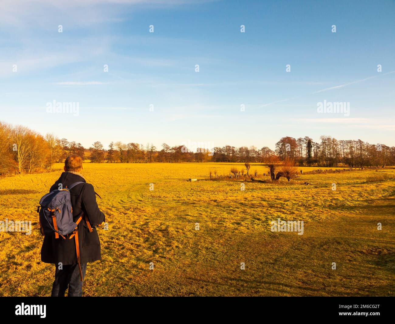 Rambling through countryside field person from behind blue sky Stock Photo