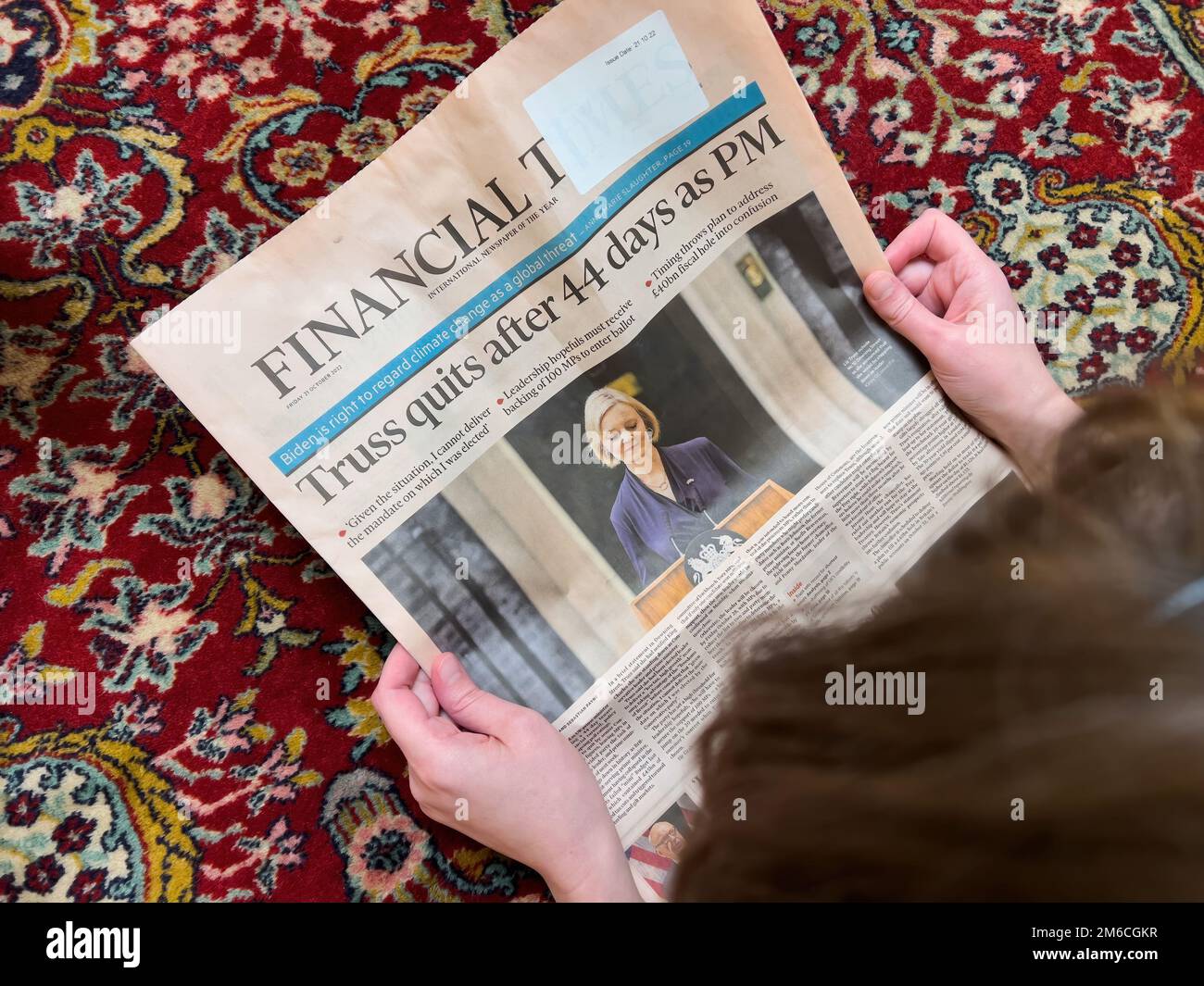 London, United Kingdom - FEb 2, 2022: Directly above view of woman reading on the living room silk rug floor latest Financial Times with headline Liz Truss quits after 44 days as British Prime-minister Stock Photo
