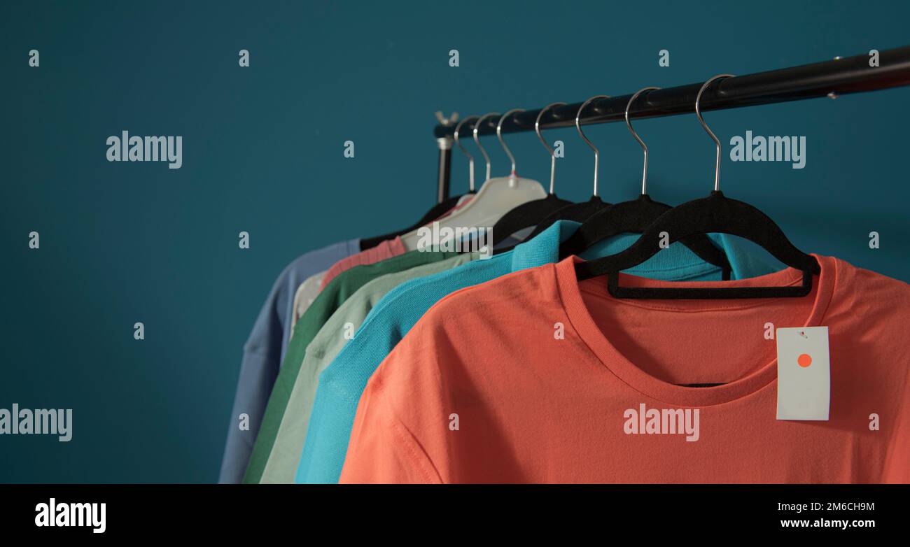 Clothes for sale are hanging on a hanger. On blue background Stock Photo