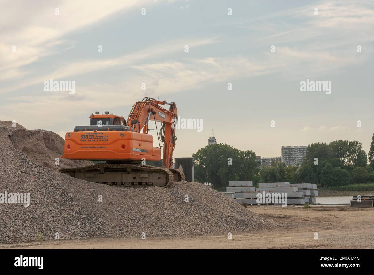 Antwerp. Flemish Region. Belgium 15-08-2021. Excavator on gravel near the riverside in the blue sky Stock Photo