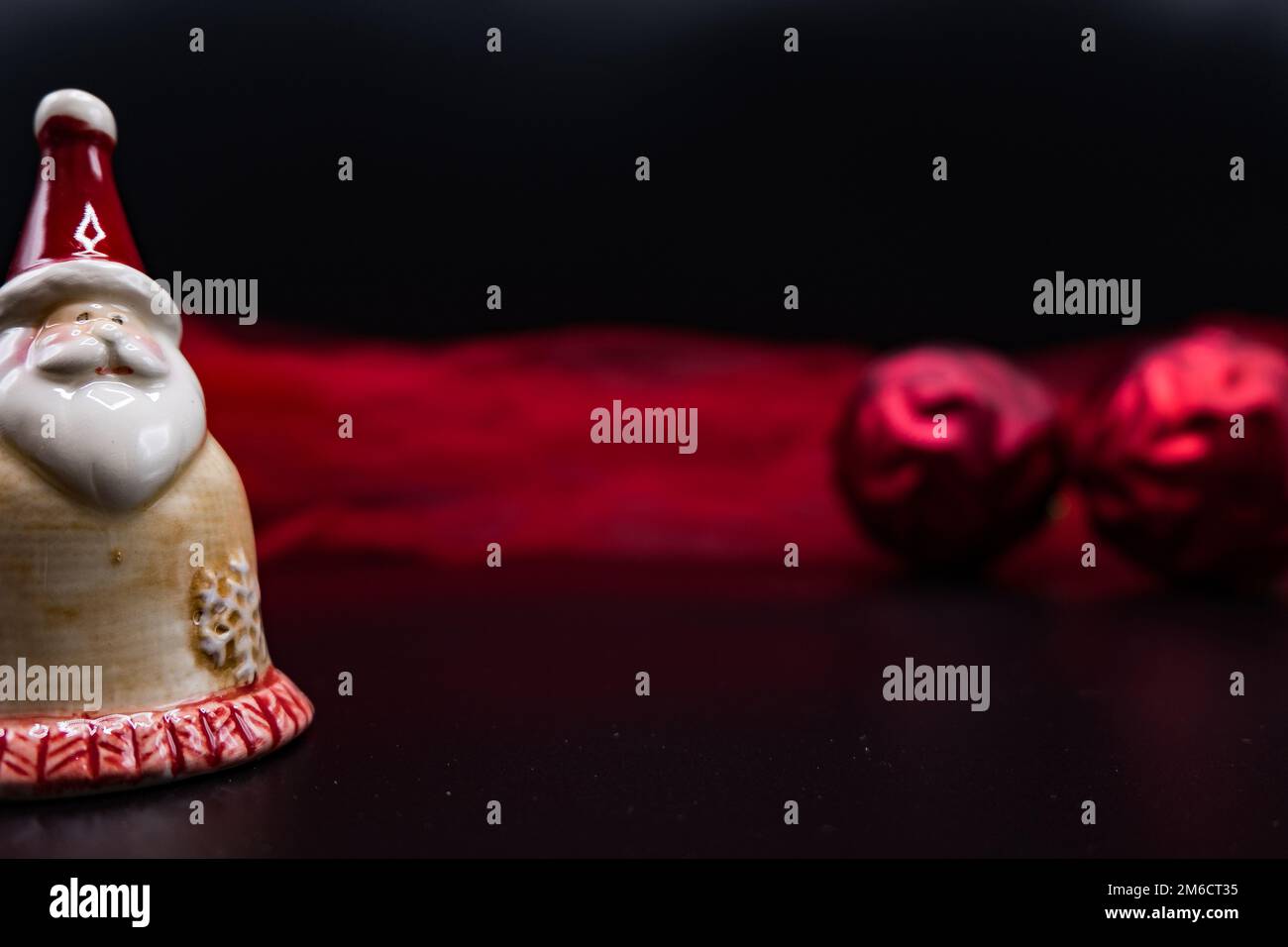 Santa Claus figure, red Christmas balls and red fabric on black. Stock Photo