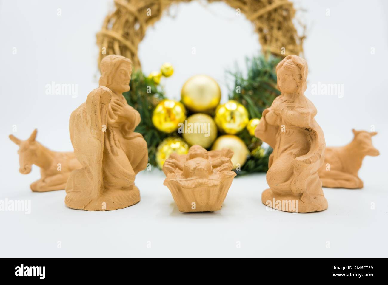 Christmas Crib. Terracotta figures of Baby Jesus, Virgin Mary, St. Joseph and wreath on white. Stock Photo