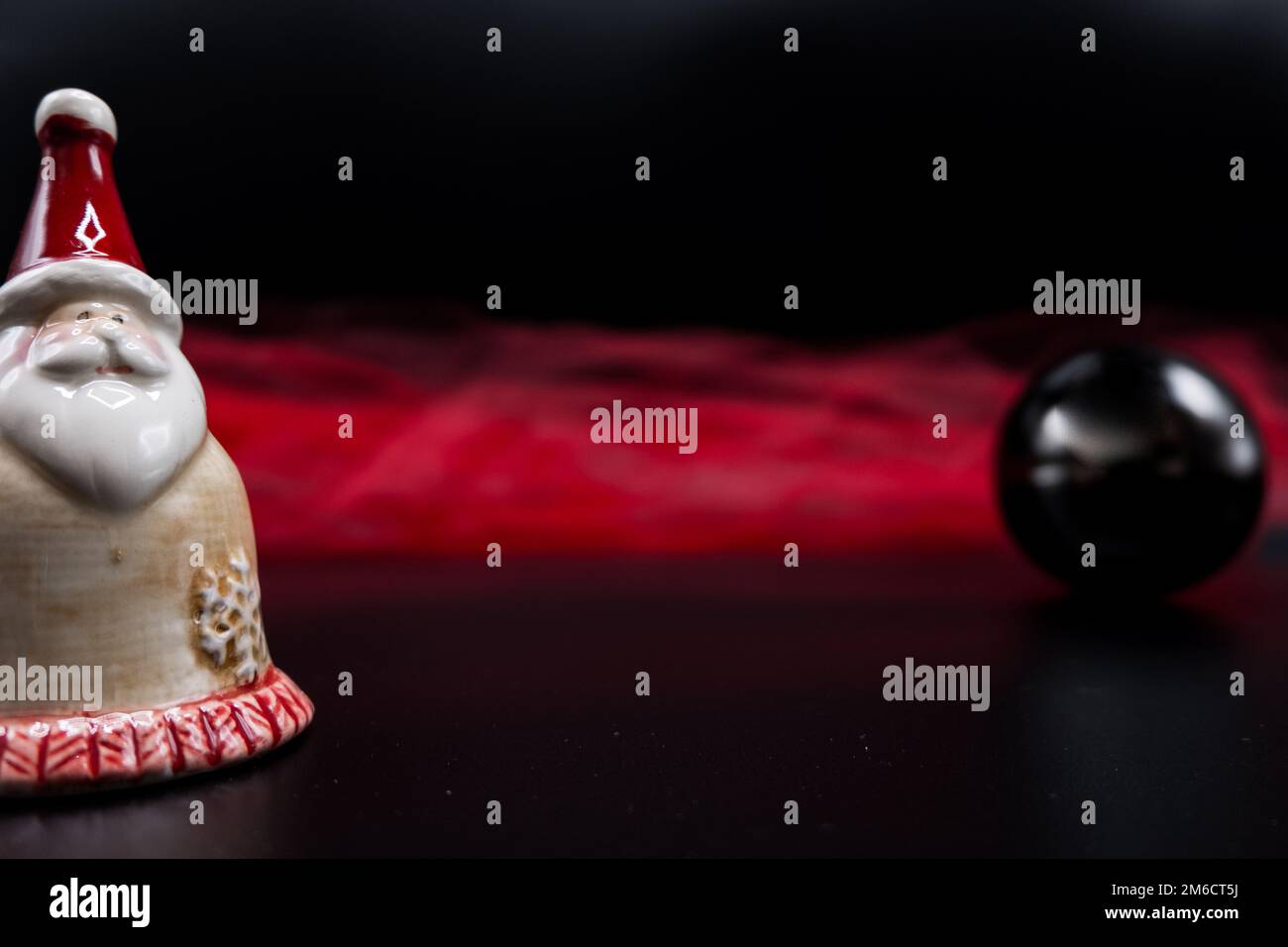 Santa Claus figure, black Christmas ball and red fabric on black. Stock Photo
