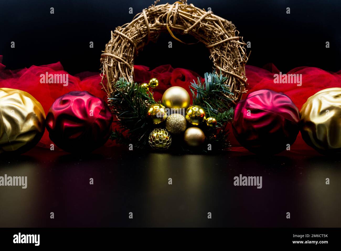 Christmas wreath and decorations with red and golden balls and fabric on black. Stock Photo