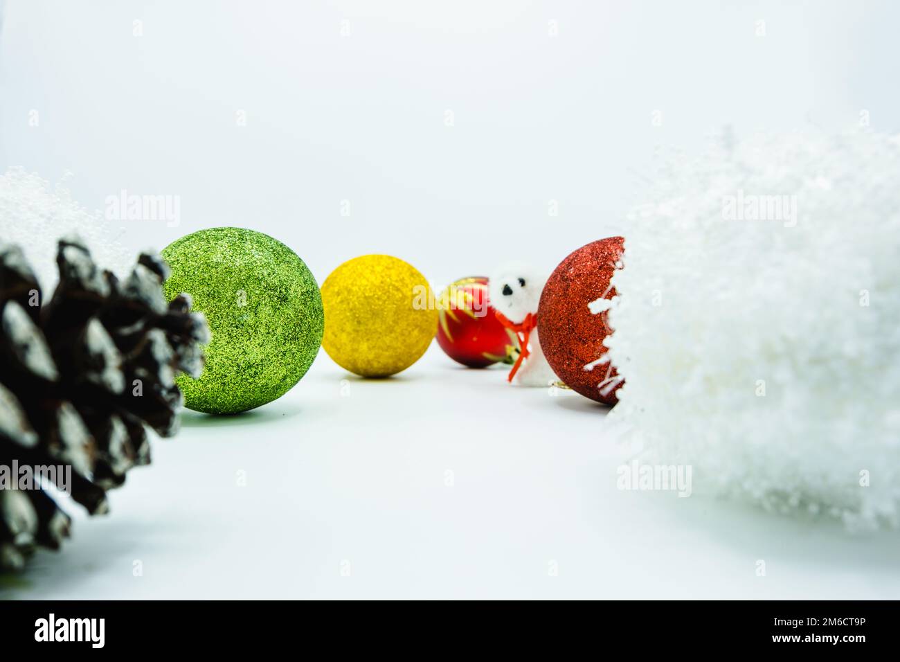 White, green, red, and yellow christmas balls with polar bear and pine cone on white. Stock Photo