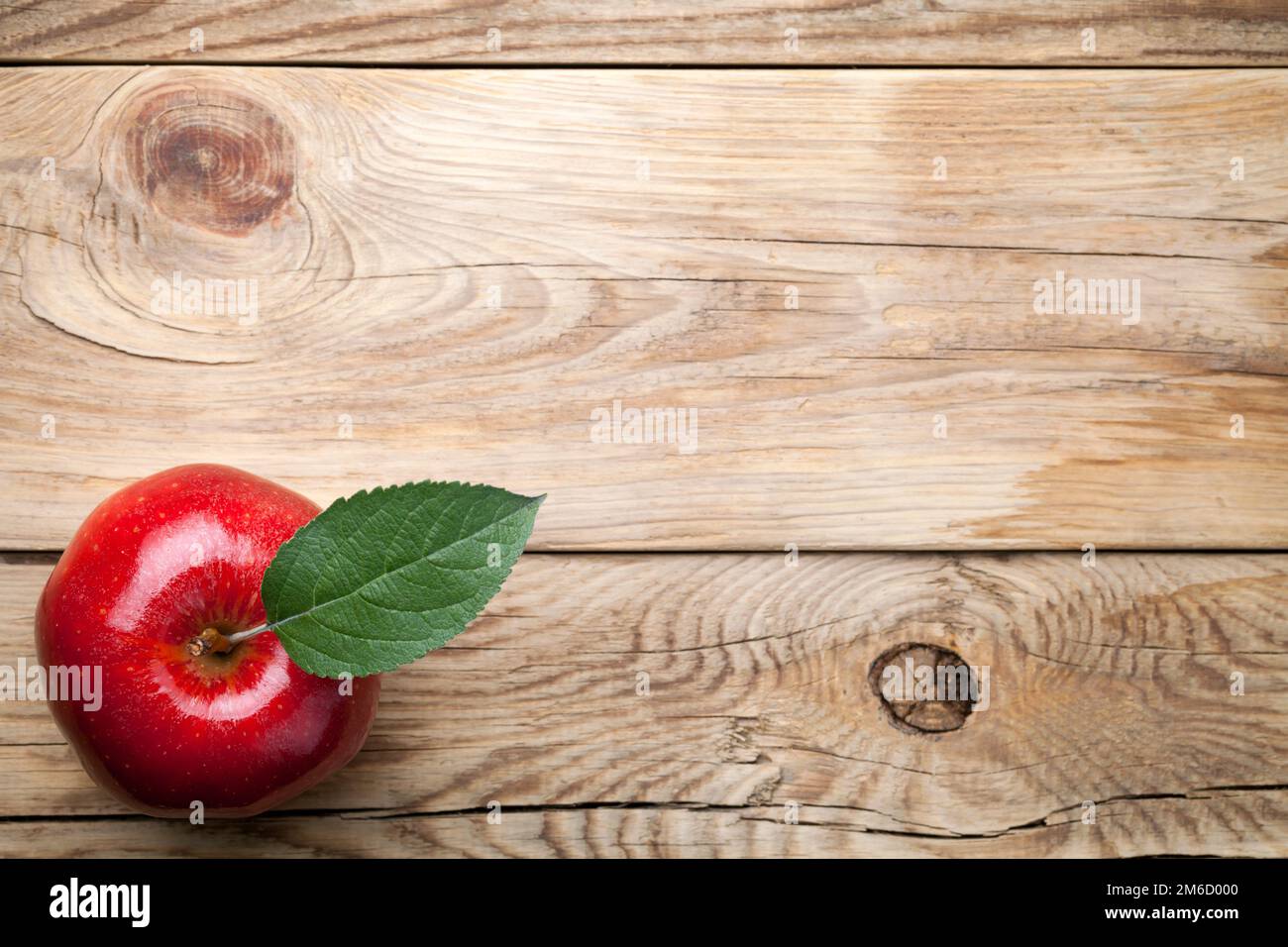 Red Apple with Green Leaf on Wooden Table Stock Photo