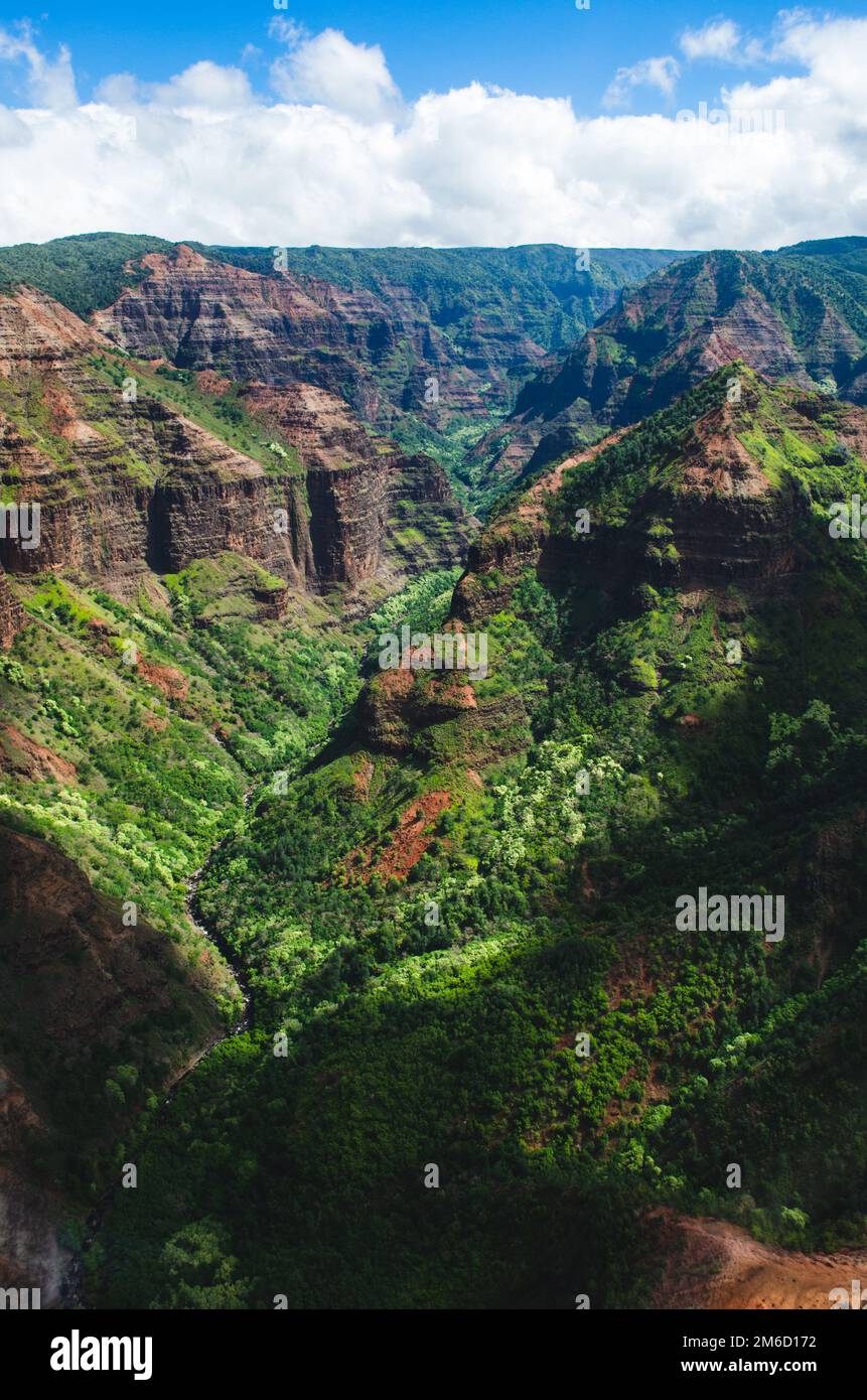 Beautiful dark green canyon, mountain range and cloudy sky in Kauai, US Stock Photo