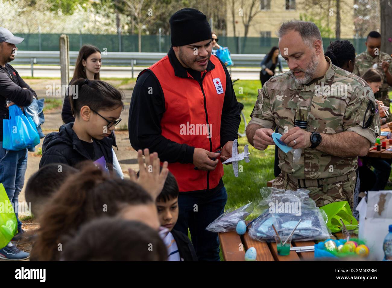 U.S. Army Pfc. Steven Alveranga, assigned to 1st Battalion, 16th Infantry Regiment, and Royal Air Force Flight Lieutenant Neal Rapson, assembles paper airplanes for the Orthodox Easter Egg Hunt hosted by the Area Support Group – Black Sea at Mihail Kogalniceanu Air Base, Romania, on April 23, 2022. The event allowed children within the community to participate in the excitement of gathering eggs, toys and candy. Stock Photo